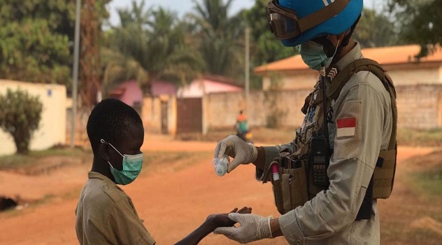 A peackeeper from the UN Multidimensional Integrated Stabilization MIssion in the Central African Republic (MINUSCA) sanitizes a little boy's hands.